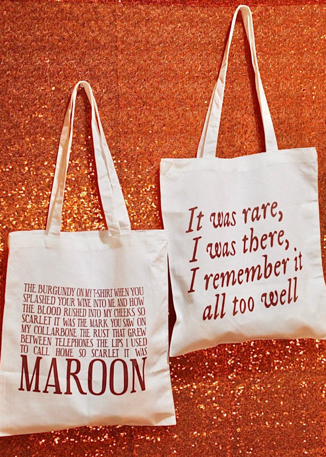 Two tote bags with text on a textured red background