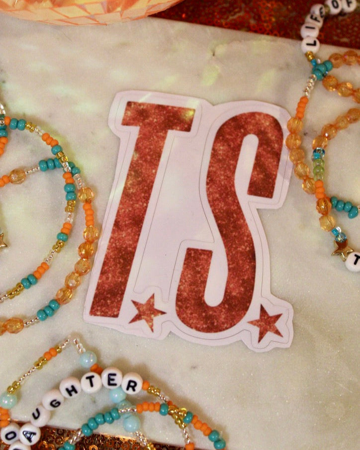 Sticker with 'TS' design on a surface with decorative items