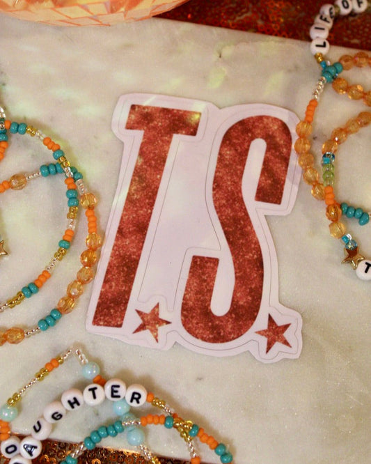 Sticker with 'TS' design on a surface with decorative items