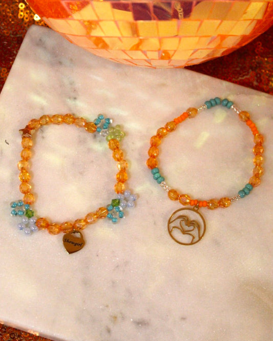 Two beaded bracelets on a marble surface with a decorative background.